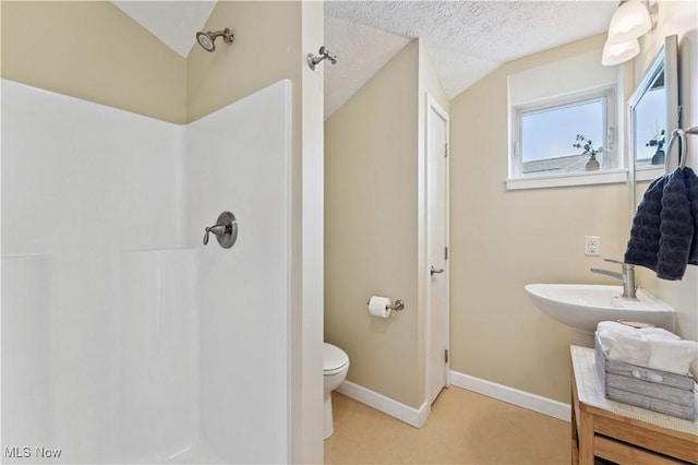 bathroom featuring toilet, vaulted ceiling, walk in shower, and a textured ceiling