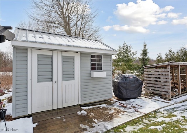 snow covered structure with a storage unit and an outbuilding