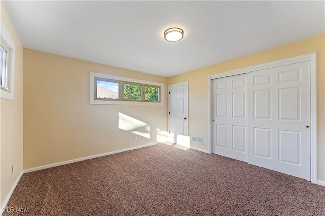 unfurnished bedroom with carpet floors, a closet, visible vents, and baseboards