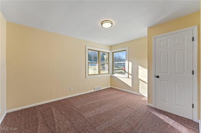 carpeted spare room featuring visible vents and baseboards