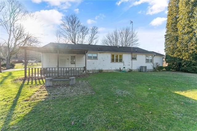 back of house with covered porch, a lawn, and central AC unit