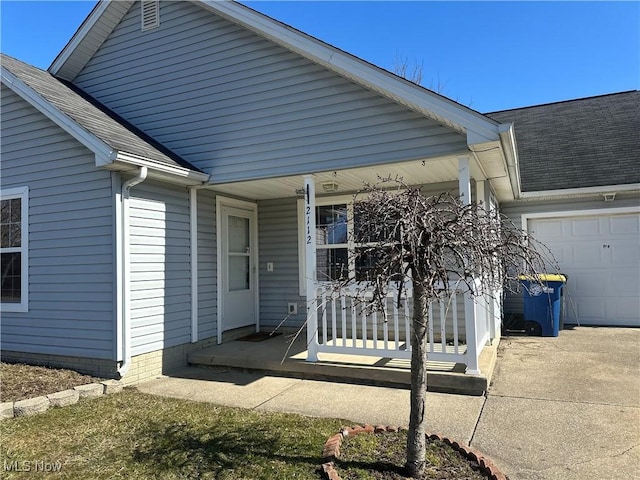 entrance to property with a garage, covered porch, and roof with shingles