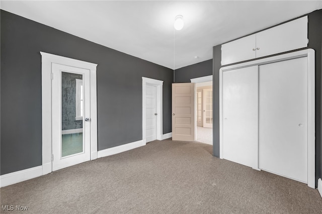 unfurnished bedroom featuring carpet floors, baseboards, and a closet