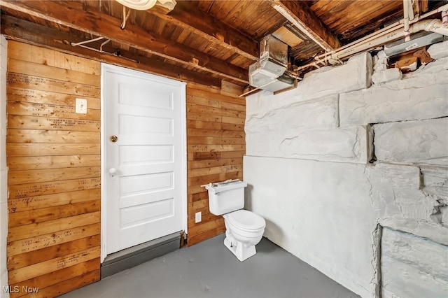 bathroom with concrete flooring, wood ceiling, wooden walls, and toilet