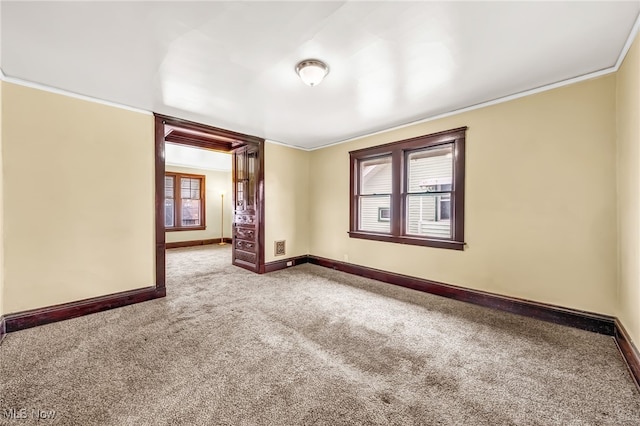 unfurnished room featuring carpet flooring, crown molding, and baseboards