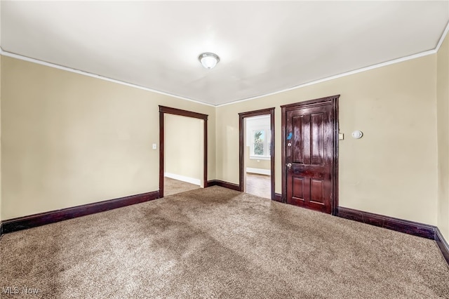 carpeted empty room with baseboards and crown molding