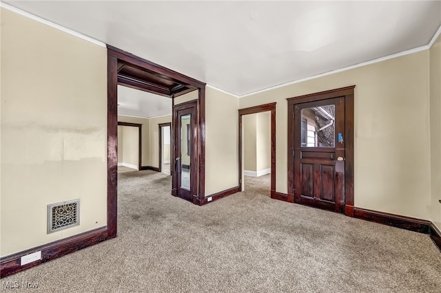 entryway with ornamental molding, visible vents, carpet floors, and baseboards