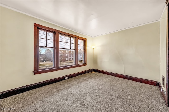 carpeted empty room featuring ornamental molding and baseboards