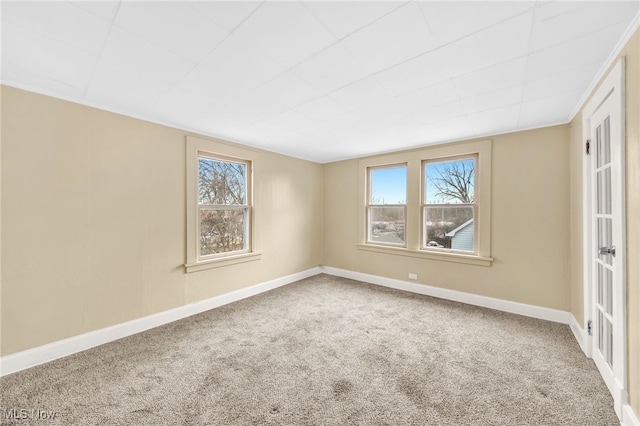 unfurnished room featuring carpet floors, baseboards, and a wealth of natural light