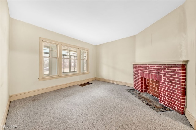 unfurnished living room with a brick fireplace, carpet flooring, visible vents, and baseboards