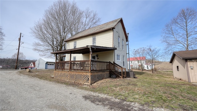 view of front of house featuring a deck, driveway, and an outdoor structure