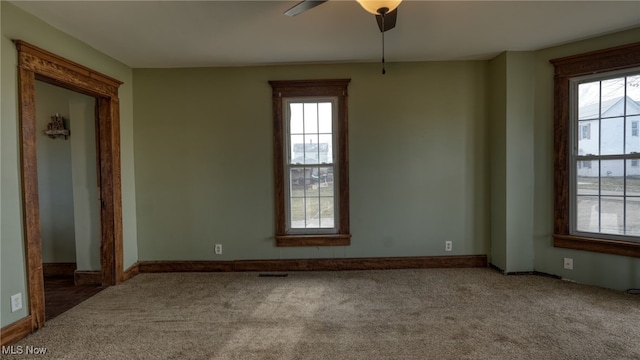 carpeted empty room featuring ceiling fan, plenty of natural light, and baseboards