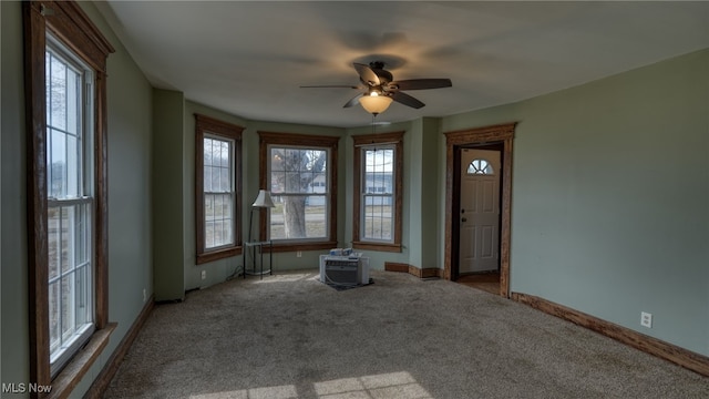 carpeted empty room featuring plenty of natural light, baseboards, and ceiling fan