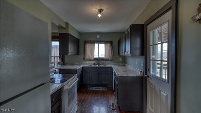 kitchen featuring a sink, visible vents, light countertops, freestanding refrigerator, and white electric range oven