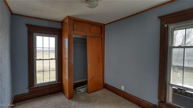 unfurnished bedroom featuring crown molding, multiple windows, cooling unit, and carpet flooring