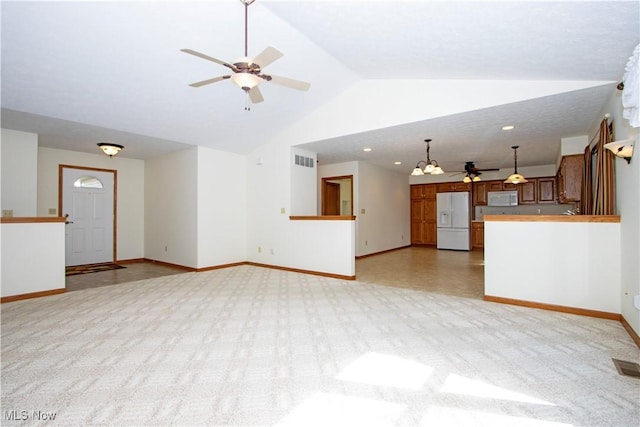 unfurnished living room featuring lofted ceiling, light colored carpet, visible vents, baseboards, and a ceiling fan