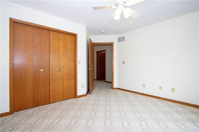 unfurnished bedroom featuring light carpet, a ceiling fan, visible vents, baseboards, and a closet