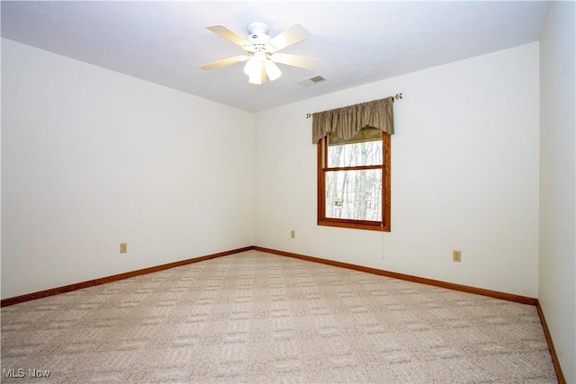 carpeted spare room featuring visible vents, baseboards, and a ceiling fan