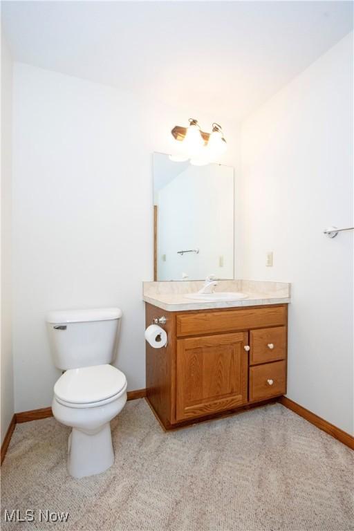 bathroom with toilet, baseboards, and vanity