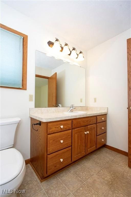 bathroom with baseboards, vanity, and toilet