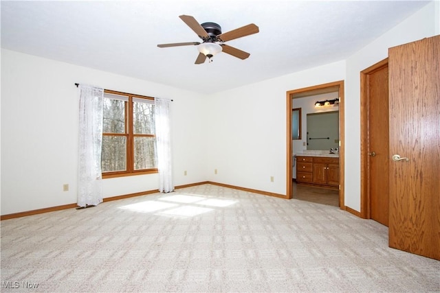 empty room with light carpet, a sink, and baseboards