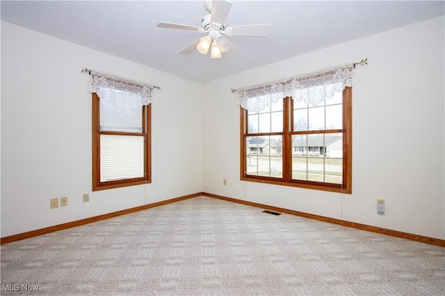 carpeted empty room featuring ceiling fan, visible vents, and baseboards