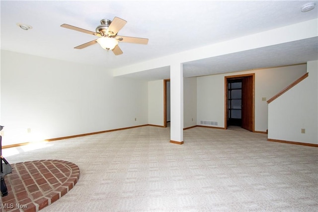 finished below grade area with light carpet, ceiling fan, visible vents, and baseboards