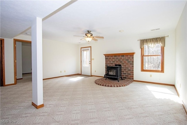 unfurnished living room featuring carpet floors, a wood stove, and baseboards