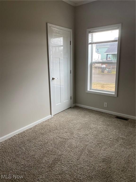 empty room featuring carpet floors, visible vents, and baseboards