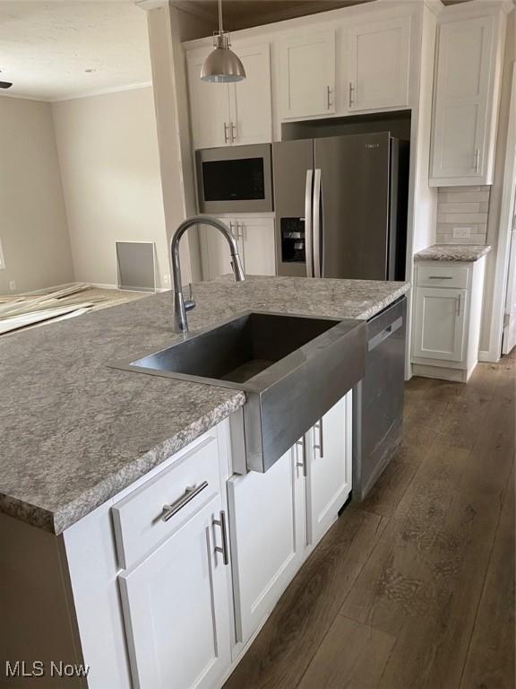 kitchen with decorative backsplash, dark wood-style flooring, stainless steel appliances, white cabinetry, and a sink