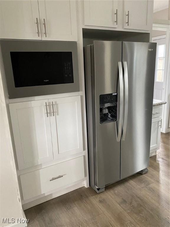 kitchen featuring wood finished floors, stainless steel fridge, white cabinetry, and built in microwave