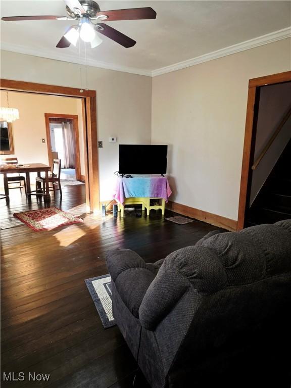 living room with ceiling fan, ornamental molding, wood-type flooring, and baseboards