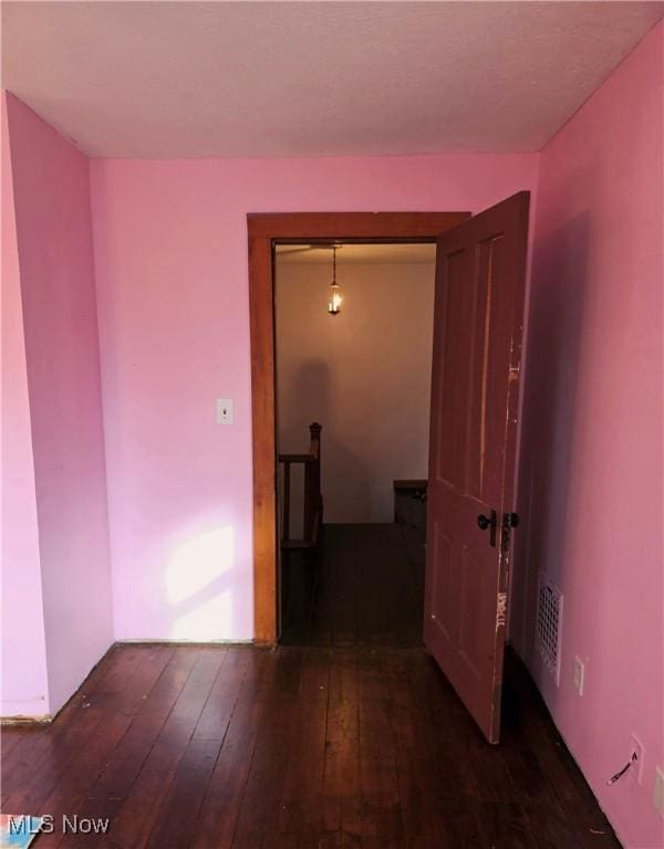 hall with visible vents, hardwood / wood-style floors, and an upstairs landing