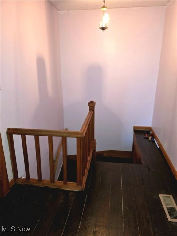 staircase featuring wood-type flooring, visible vents, and baseboards