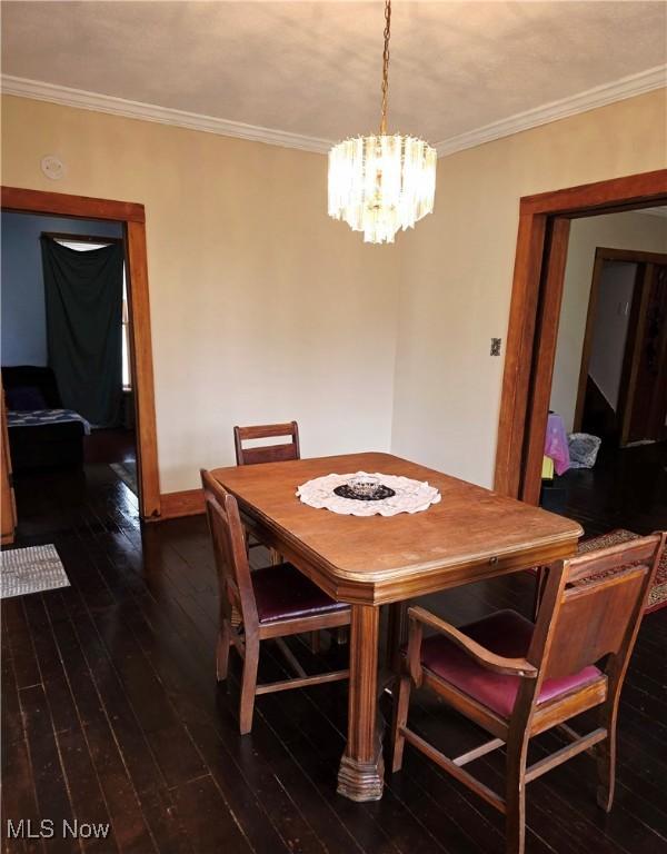 dining room featuring crown molding, a chandelier, and dark wood-type flooring