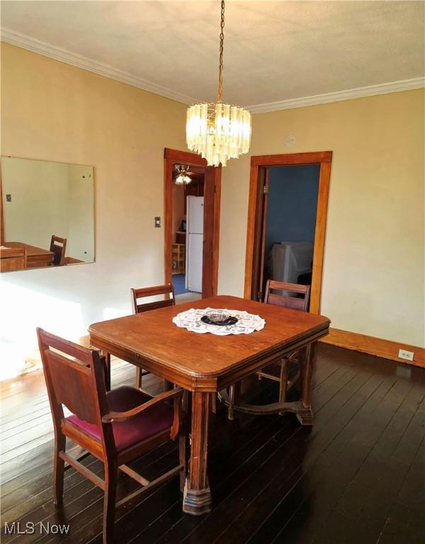 dining space featuring dark wood-style floors, an inviting chandelier, and crown molding