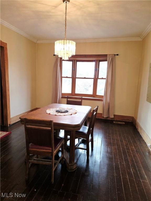 dining space featuring baseboards, wood-type flooring, an inviting chandelier, and crown molding