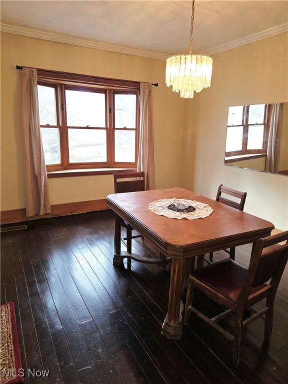 dining space featuring dark wood-type flooring, a wealth of natural light, a chandelier, and crown molding