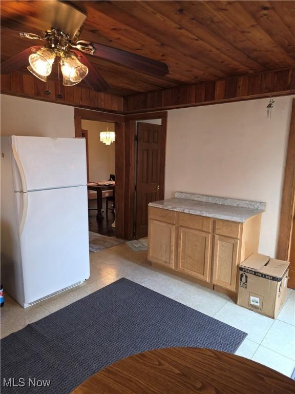 kitchen featuring wood ceiling, light tile patterned flooring, freestanding refrigerator, and a notable chandelier