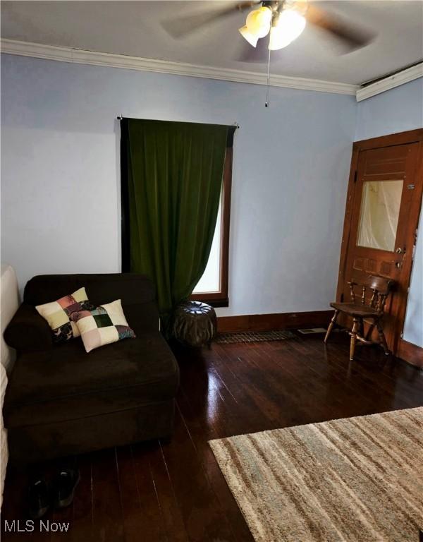 sitting room featuring baseboards, wood-type flooring, a ceiling fan, and crown molding