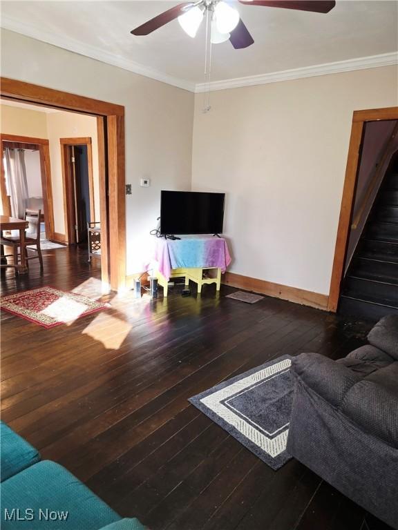 living room featuring wood-type flooring, baseboards, and crown molding