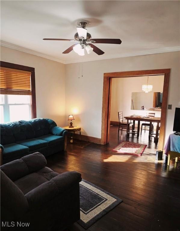 living room featuring ceiling fan with notable chandelier, crown molding, baseboards, and hardwood / wood-style flooring