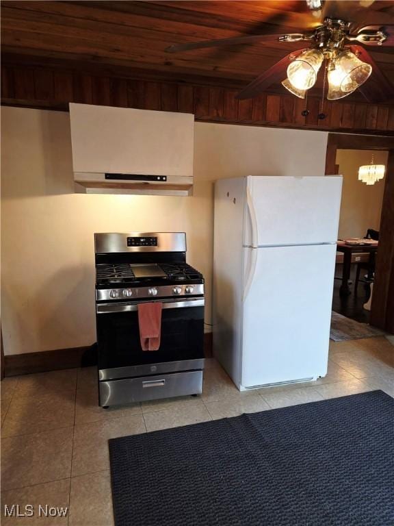 kitchen featuring light tile patterned floors, wood ceiling, freestanding refrigerator, under cabinet range hood, and gas stove