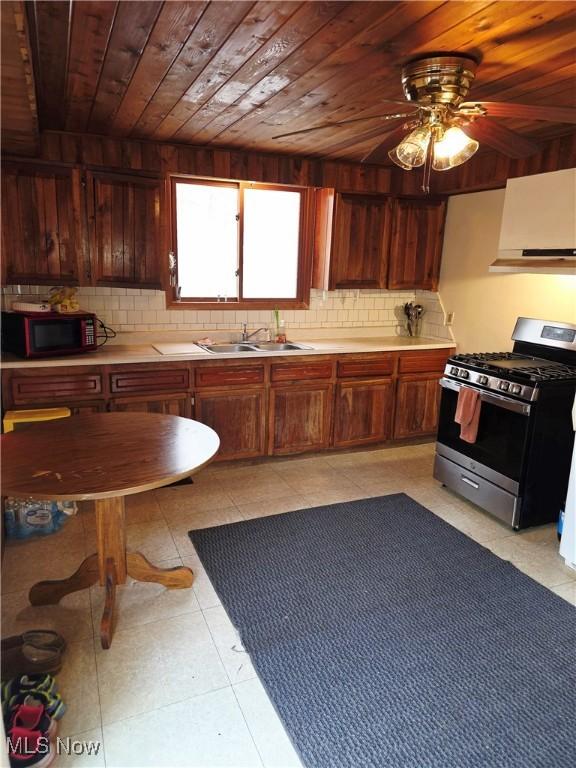 kitchen with a sink, wood ceiling, light countertops, stainless steel gas stove, and tasteful backsplash