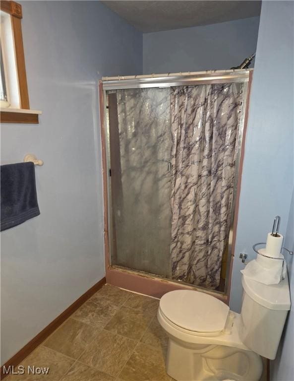 full bathroom featuring a stall shower, toilet, and baseboards