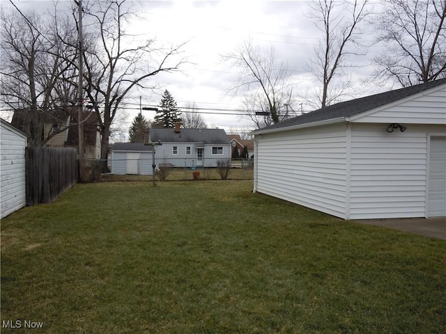 view of yard featuring a garage, a fenced backyard, and an outbuilding