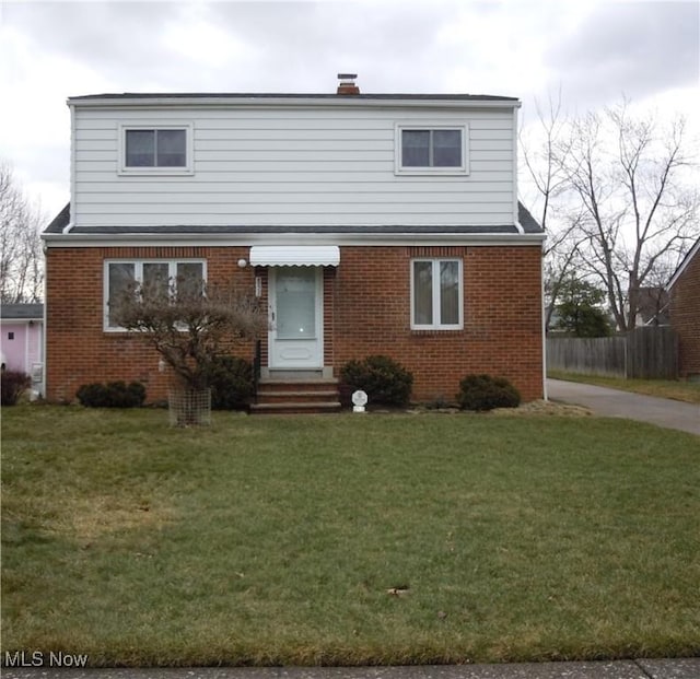 view of front facade featuring entry steps, brick siding, fence, and a front yard