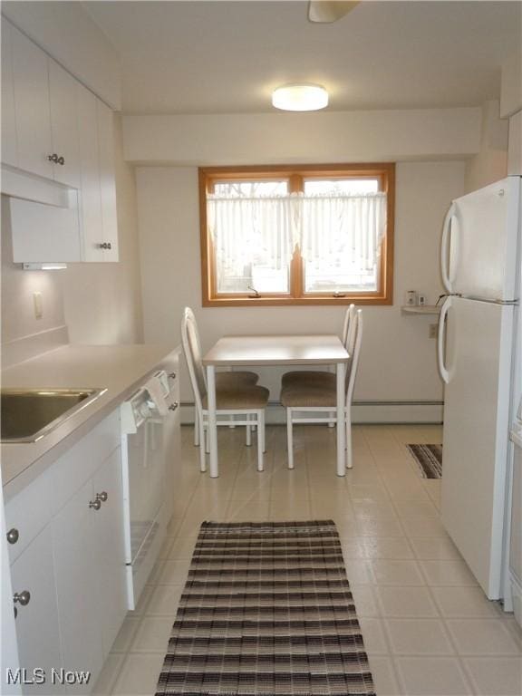 kitchen featuring light countertops, freestanding refrigerator, white cabinets, and dishwasher