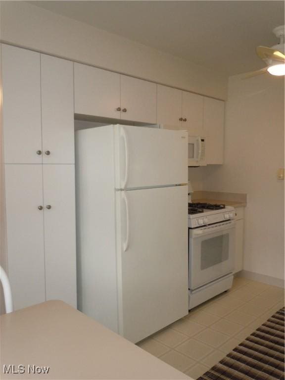 kitchen with light tile patterned floors, light countertops, white appliances, and white cabinetry