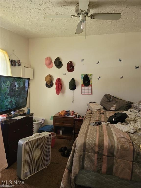 bedroom with carpet, ceiling fan, and a textured ceiling